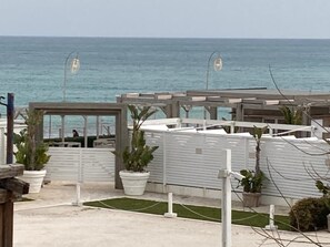 Una propiedad frente a la playa con un área de estar cubierta al aire libre, plantas en macetas y vista al mar.