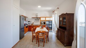 Eine Küche mit Esstisch, Stühlen, einem Kühlschrank und einem Holzschrank.