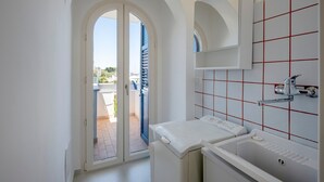Ein modernes Badezimmer mit Waschmaschine, Waschbecken und Dusche.