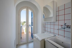 Un bagno moderno completo di lavatrice integrata, lavabo e doccia.