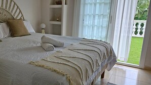 A bed with a woven headboard, white bedding, and a rolled towel. - Villa "Ainara Luxury" with Mountain View, Private Pool & Wi-Fi (LLORETR DE MAR)