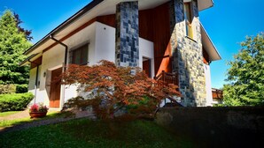 A modern house with a stone facade, a wooden deck, and a well-maintained garden.