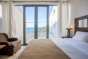 A bedroom with a bed, a sofa, a lamp, and a view through a glass door.