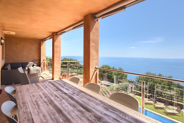 Un comedor con mesa y sillas de madera, un sofá y vista al mar.