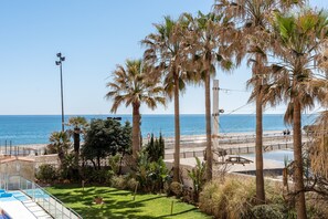 Une piscine avec vue sur la mer, les palmiers et la plage.