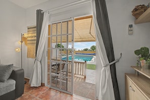 A room with a sliding glass door leading to an outdoor area with a pool and a covered patio.