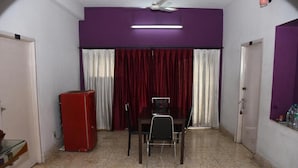 Une pièce comprenant une table et des chaises, un réfrigérateur rouge et un ventilateur de plafond.