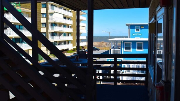 A view from a balcony overlooking a building with multiple balconies and a blue building labeled "WINDJAMMER" in the background. - Old Wharf 15 1 Bedroom Condo by RedAwning (Ocean City)