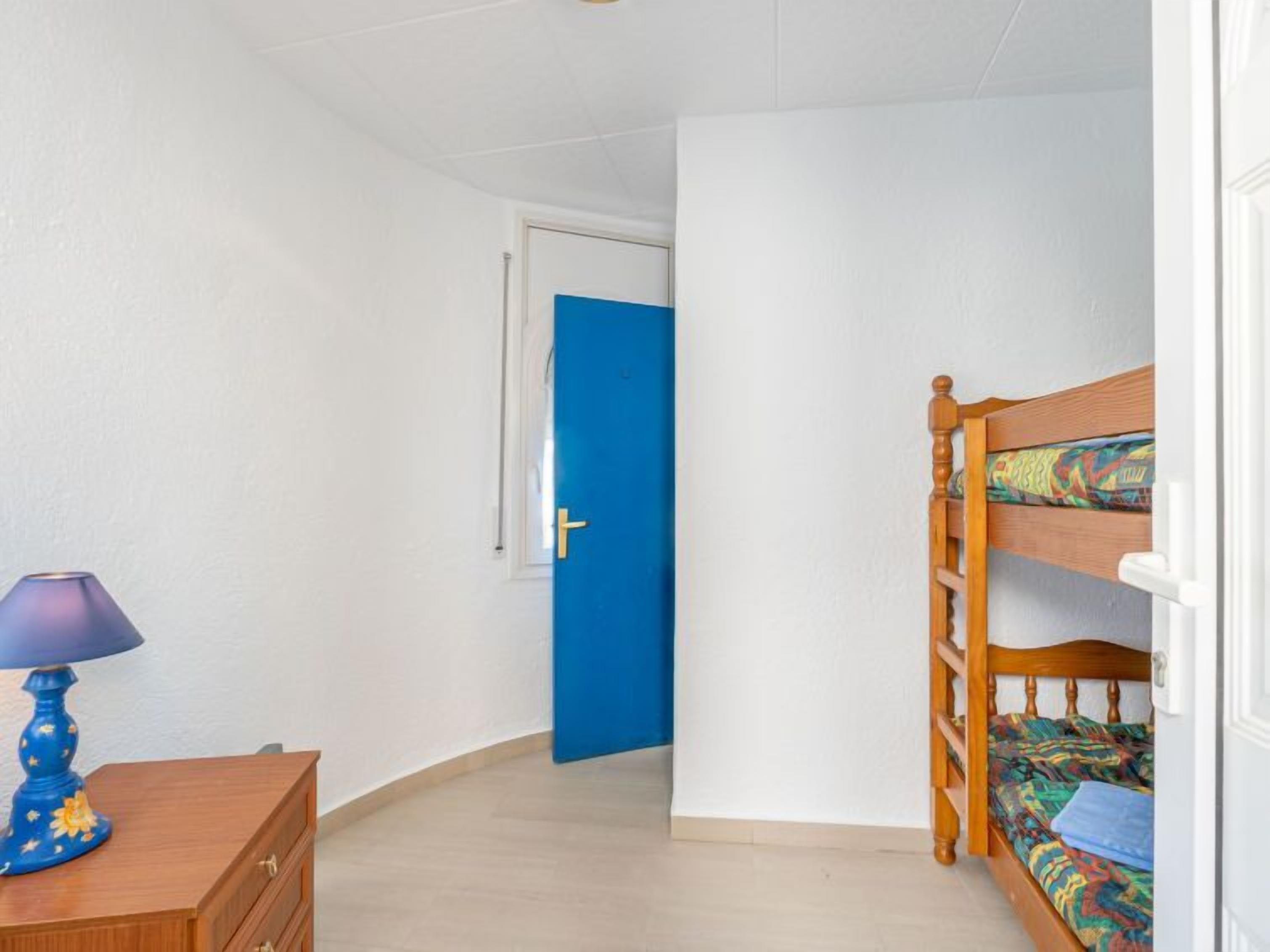 Ein Zimmer mit einem Etagenbett, einem Holzschrank und einer blauen Tür.