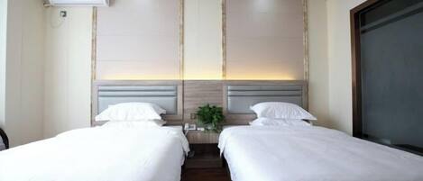 A hotel room with two beds, a nightstand, a plant, and a large window.