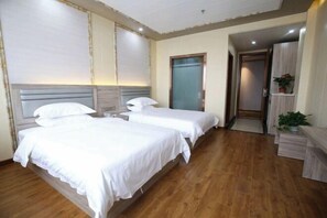 A hotel room with two beds, a wooden floor, a door leading to another room, and a small plant on a side table. - Hongfuxuan Hotel (Jurong)