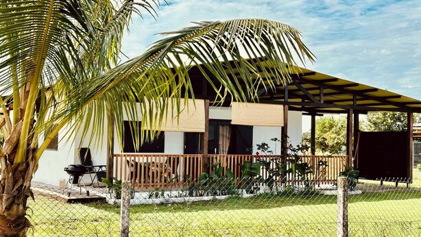 Ein modernes Haus mit überdachter Terrasse, Grill und umzäunter Garten.