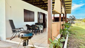 Eine Terrasse im Freien mit Grill, Stühlen und Tisch.