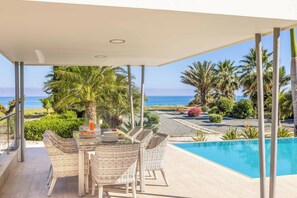 A covered outdoor area with a pool, wicker furniture, and a view of the ocean. - Limni Beach Villa - Four Bedroom Villa, Sleeps 8 (Polis)