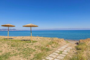 A beach with two thatched umbrellas, a clear blue sky, and a distant mountain range. - Limni Beach Villa - Four Bedroom Villa, Sleeps 8 (Polis)