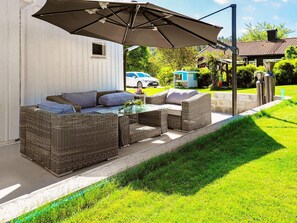 A patio with wicker furniture, a table, and a large umbrella. - 4 Star Holiday Home in Kallekarr (Kållekärr)