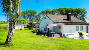 Ein Haus mit Terrasse, Pool und Rasenfläche.