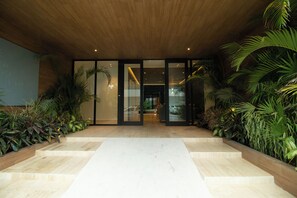 A modern building entrance with a wooden ceiling, glass doors, and a central marble pathway.