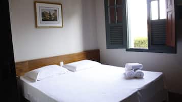 A neatly made bed with white linens and a picture frame on the wall.
