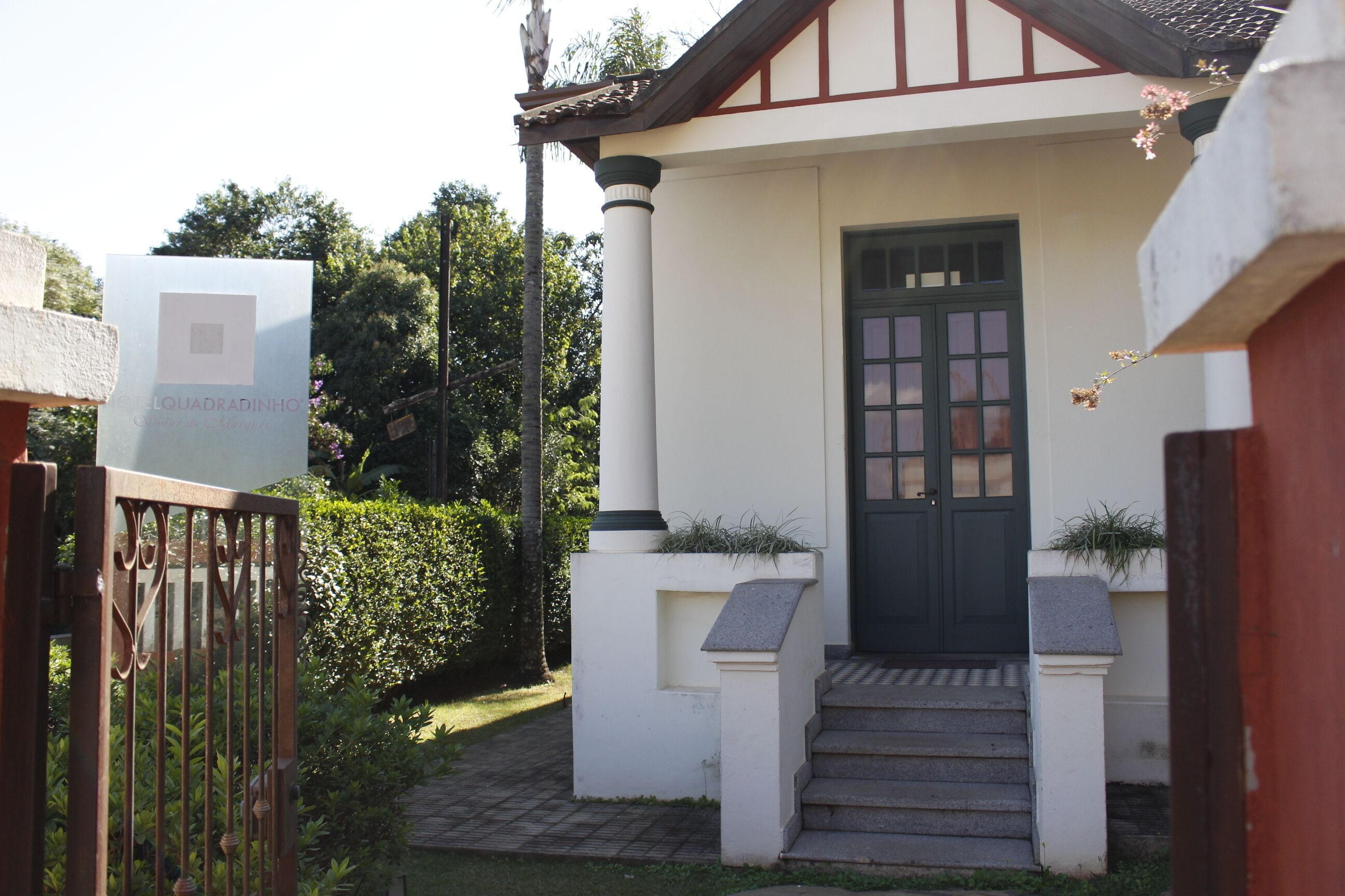 Um edifício com porta verde escura, paredes brancas e um pequeno lance de degraus que leva à entrada.