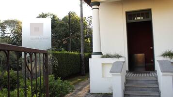 Entrada de un edificio con un letrero que dice "QUADRADINHO" y una escalera que lleva a la puerta.