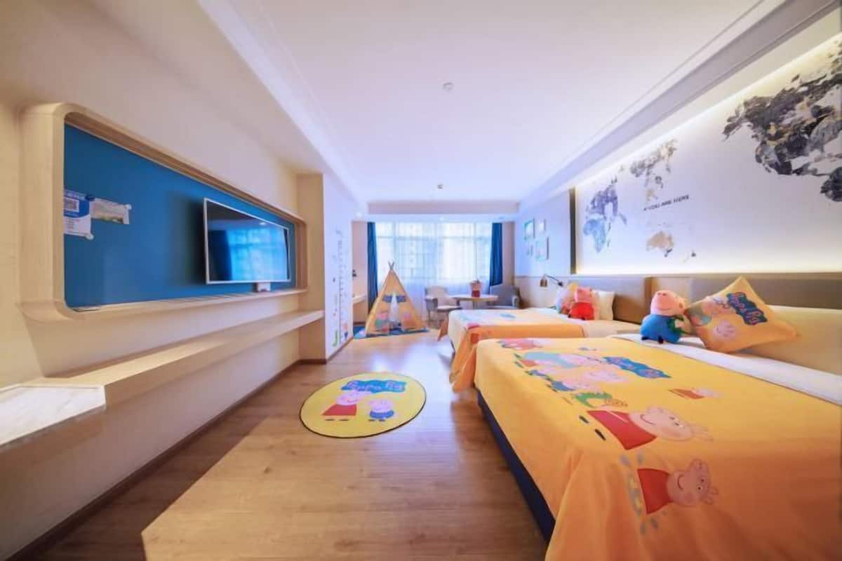A hotel room with two beds, a TV, a desk, and a window.