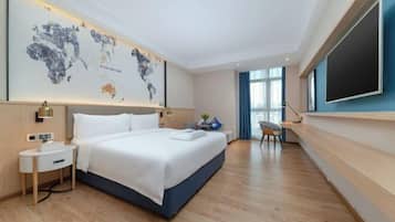 Une chambre d’hôtel moderne dotée d’un grand lit, d’un bureau, d’une chaise, d’une œuvre d’art représentant une carte du monde et d’un téléviseur fixé au mur.