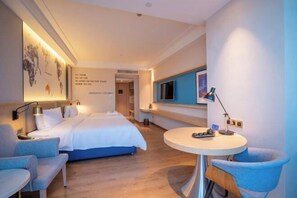 A modern hotel room with a large bed, a round table, and a TV. - Kyriad Marvelous Hotel (Heyuan)