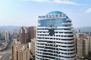 A modern hotel with a distinctive curved facade and a prominent sign at the top. - Kyriad Marvelous Hotel (Heyuan)