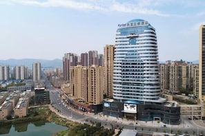 A modern hotel with a curved facade, multiple floors, and a prominent sign at the top. - Kyriad Marvelous Hotel (Heyuan)