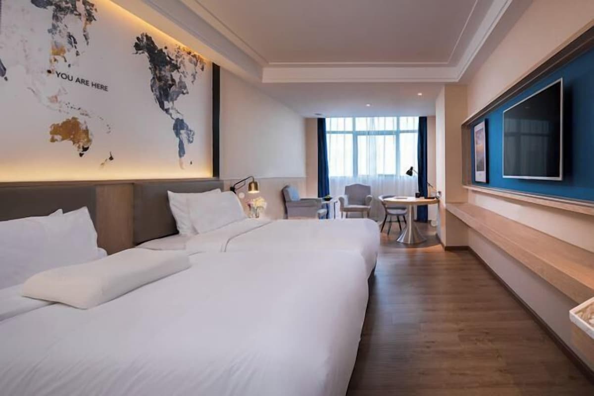 Een hotelkamer met een groot bed, een bureau, een stoel, een televisie en een wereldkaart aan de muur.