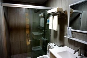 Une salle de bain moderne avec une douche à parois de verre, un lavabo blanc et un miroir.
