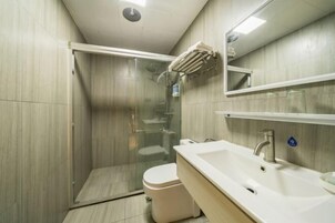 Un baño moderno con ducha envuelta en vidrio, un lavabo blanco y un inodoro.