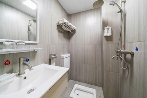 Un baño con lavabo, espejo, toallero, ducha e inodoro.
