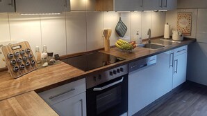 A modern kitchen with a wooden countertop, built-in appliances, and a backsplash.