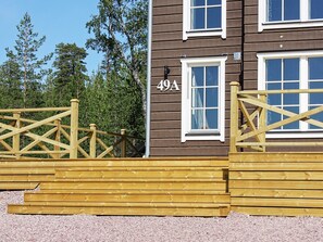 A wooden building with a number '49A' on the side, a gated entrance, and a clear view of trees in the background.