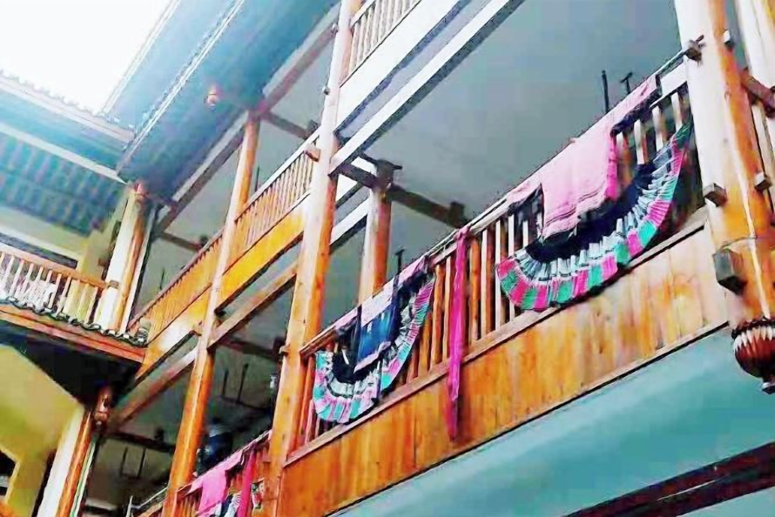 A multi-story building with balconies, wooden railings, and colorful fabric decorations.