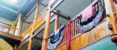 A multi-story building with balconies, wooden railings, and colorful fabric decorations.