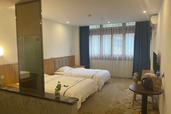 A hotel room with two beds, a small table, a chair, a desk, a mirror, and a window with curtains. - Longsheng Yuntian Grand Hotel (Longsheng)