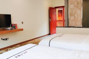 A hotel room with two beds, a TV on a shelf, and a door leading to a bathroom. - Longsheng Yuntian Grand Hotel (Longsheng)