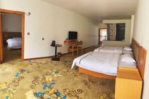 A hotel room with two beds, a desk with a television, a small table with a kettle, and a patterned carpet. - Longsheng Yuntian Grand Hotel (Longsheng)