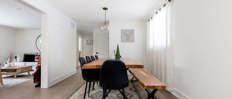 Un coin repas avec une table en bois, des chaises noires et un tapis à motifs.