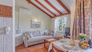 Un coin repas accueillant avec une table dressée pour deux personnes, un canapé et un téléviseur.