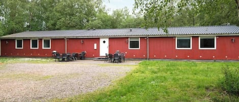 A red building with a gravel driveway and a grassy area in front.