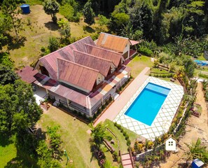 Une grande maison avec une piscine, entourée d’une végétation luxuriante et d’un jardin bien entretenu.