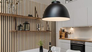 A modern kitchen with a white countertop, black pendant light, and a wine bottle on the table. - 6 Person Holiday Home in Gjern-by Traum (Gjern)