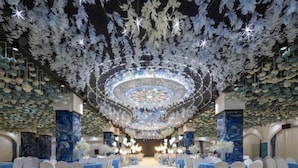 A formal event space with a central stage, rows of white chairs, and a ceiling adorned with hanging decorations. - Fengtai Hotel (Zhangwu)