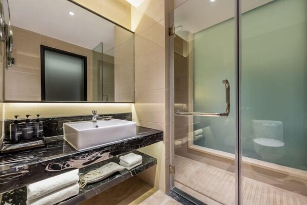 A modern bathroom with a large mirror, a white sink, a glass shower enclosure, and a marble countertop. - Fengtai Hotel (Zhangwu)