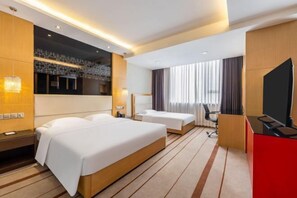 A hotel room with a large bed, a desk, a chair, and a TV.