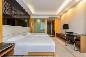 A modern hotel room with a large bed, a desk, and a chair.